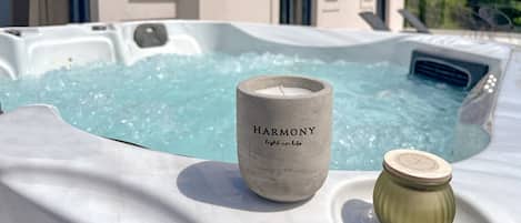 A hot tub with a candle labeled "HARMONY" and a small jar beside it.