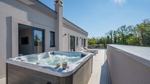 A modern building with a hot tub on the patio, large windows, and a clear sky. - Villa Kalea With Pool (Labin)