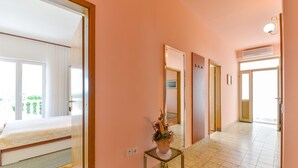 Passadís d'hotel amb un llit a l'habitació esquerra, una taula petita amb una planta i una porta que condueix a una altra habitació.