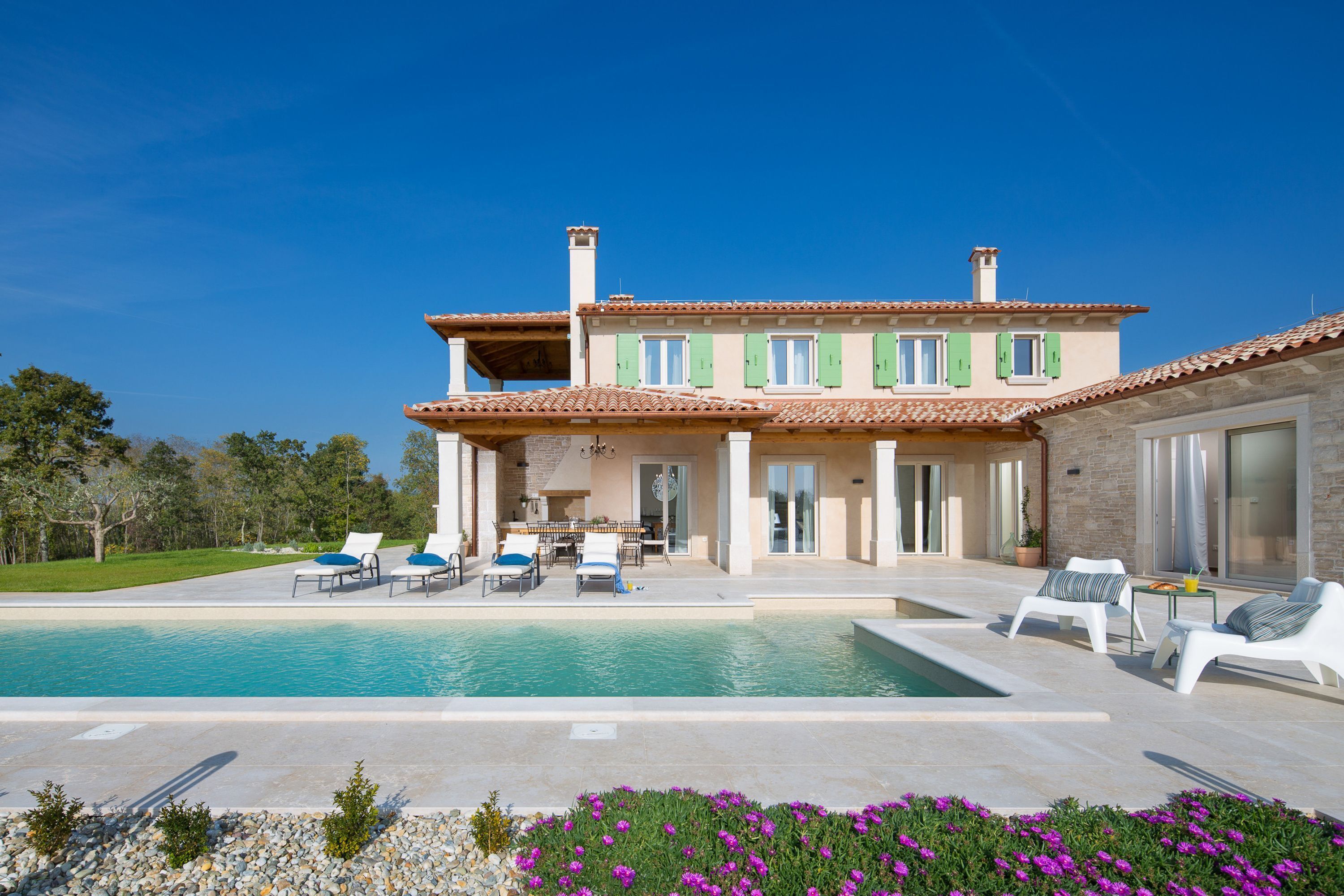 Uma casa de dois andares com piscina, área de estar externa e jardim.
