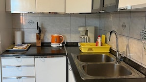 Eine moderne Küche mit weißen Schränken, einer schwarzen Arbeitsplatte und einem Edelstahl-Spülbecken.