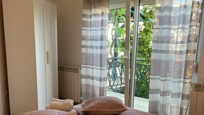 Ein Schlafzimmer mit einem großen Bett, einem Kleiderschrank und einer Glasschiebetür, die auf einen Balkon führt.