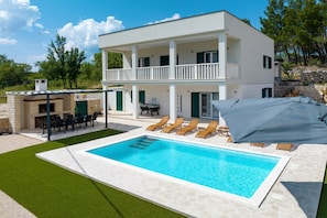 A two-story white building with a swimming pool, outdoor seating, and a covered area. - Villa Vallis With Pool (Obrovac)