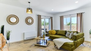 A modern living room with a green sofa, wooden coffee table, and two wall-mounted mirrors. - Villa Rea 4 With Heated Pool (Privlaka)