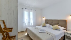 A neatly arranged bedroom with a bed, bedside tables, and a window with curtains. - Villa Rea 4 With Heated Pool (Privlaka)