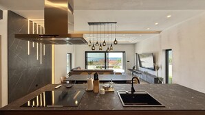 Una cocina moderna con una isla central, horno empotrado y un amplio ventanal con vista al mar.