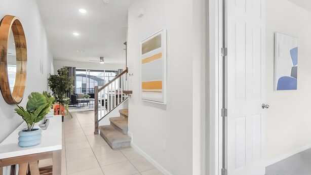 Un interior moderno con una escalera, paredes blancas y una puerta decorada con una pintura geométrica.