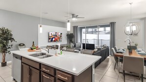Una cocina moderna con una isla central, electrodomésticos integrados y un comedor con un amplio ventanal.