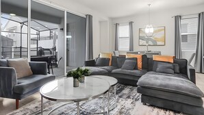 Una sala de estar moderna con un sofá modular, una mesa de centro de vidrio y un comedor con mesa y sillas.
