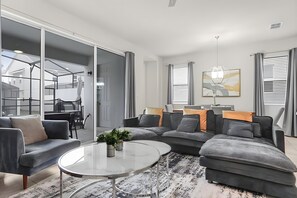 Ein modernes Wohnzimmer mit einem Ecksofa, einem Glastisch und einem Essbereich mit Tisch und Stühlen.