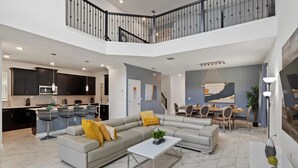 Een ruime woonkamer met een grijze modulaire bank, een salontafel en een eethoek met een groot schilderij.