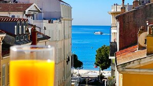 Un paysage urbain côtier avec des bâtiments, un ciel bleu dégagé et une vue sur la mer.