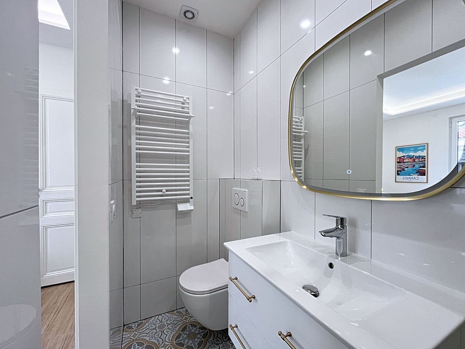 Une salle de bain moderne avec un lavabo blanc, des toilettes, un porte-serviettes et un miroir.
