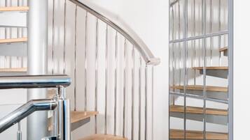 A modern staircase with wooden steps and metal railings, leading to a landing with a glass partition.