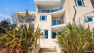 Un immeuble à plusieurs étages doté de balcons, d’un escalier et de plantes tropicales.
