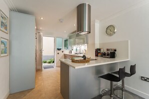 A modern kitchen with a central island, stainless steel appliances, and a visible clock.