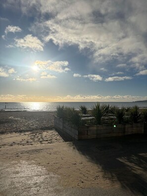A beach with a concrete planter with plants, a sandy area, and the ocean in the background. - Pinewood Retreat - Garden Apartment Close To Beach (Branksome Park)