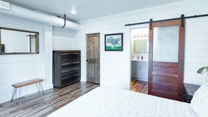 Een slaapkamer met een bed, een houten kast, een schuifdeur, een lijstbeeld en een schilderij.