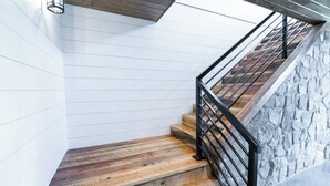 Een trap met houten treden en een stenen muur, voorzien van een metalen leuning.