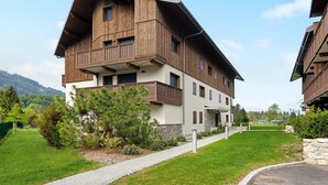 A multi-story building with a sloped roof, wooden exterior, and a balcony on the second floor.