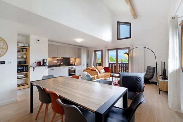 A modern living space with a dining area, kitchen, and seating area with a view.