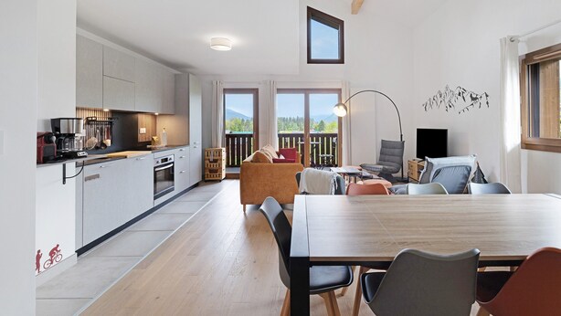A modern kitchen with a dining area, large windows, and a view of mountains.