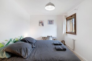 A bedroom with a bed, a desk, and a window.