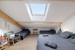 Un dormitorio estilo loft con tragaluz, dos camas individuales, un escritorio y una silla.