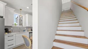 Eine moderne Küche mit weißen Schränken, einer Holztreppe und einem Stuhl.