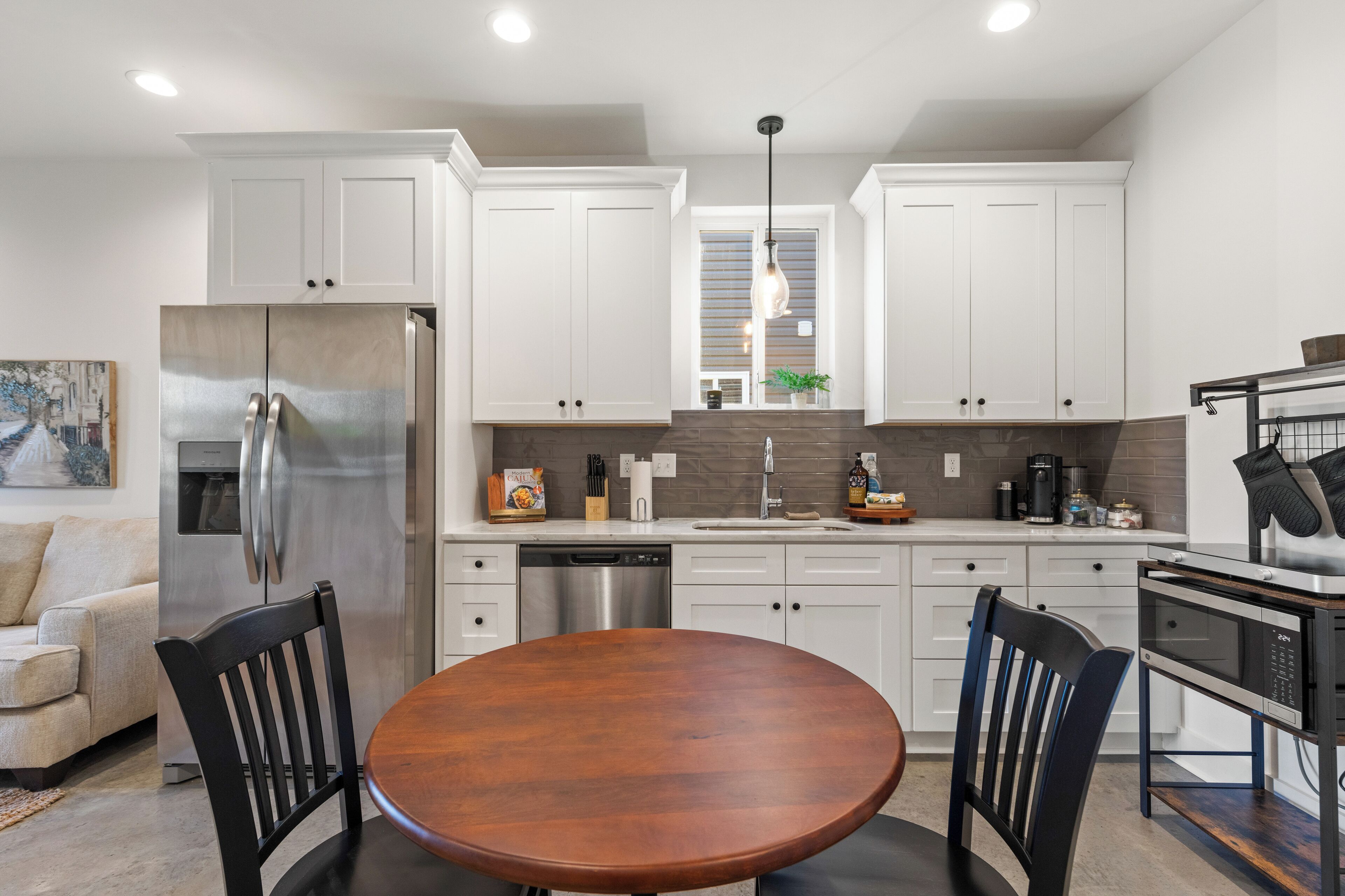 Una cocina moderna con armarios blancos, electrodomésticos de acero inoxidable y una mesa de comedor de madera.