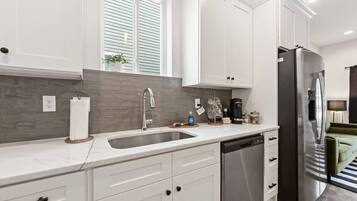 A modern kitchen with white cabinetry, a stainless steel refrigerator, and a built-in dishwasher.
