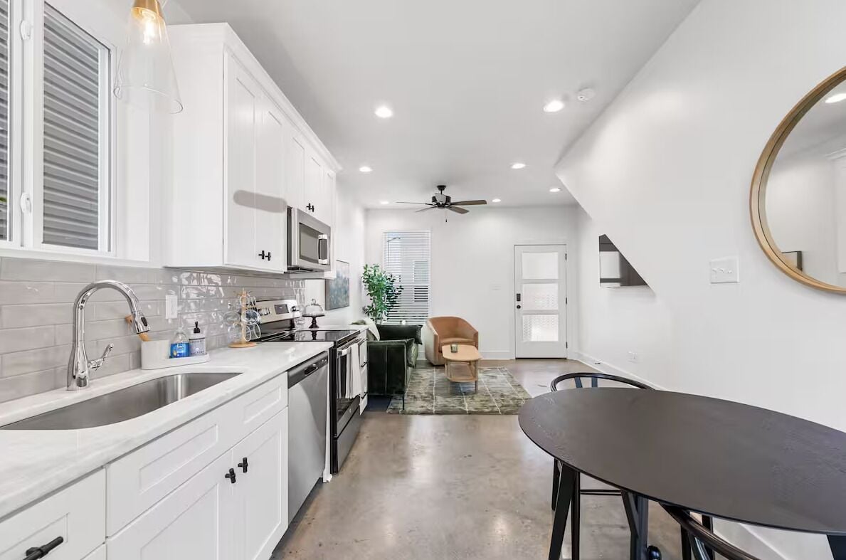 Une cuisine moderne avec des armoires blanches, un comptoir noir et un ventilateur de plafond.
