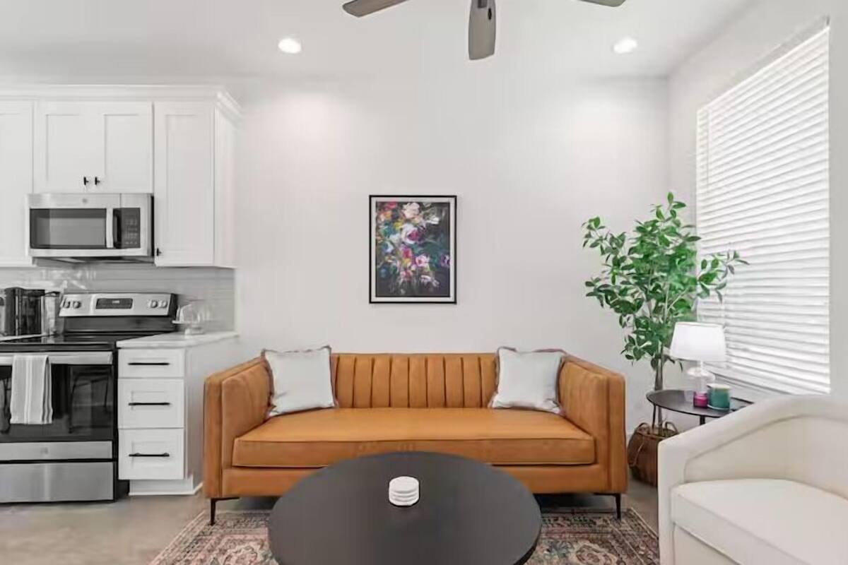 A modern living room with a sofa, a coffee table, and a kitchen area with appliances.