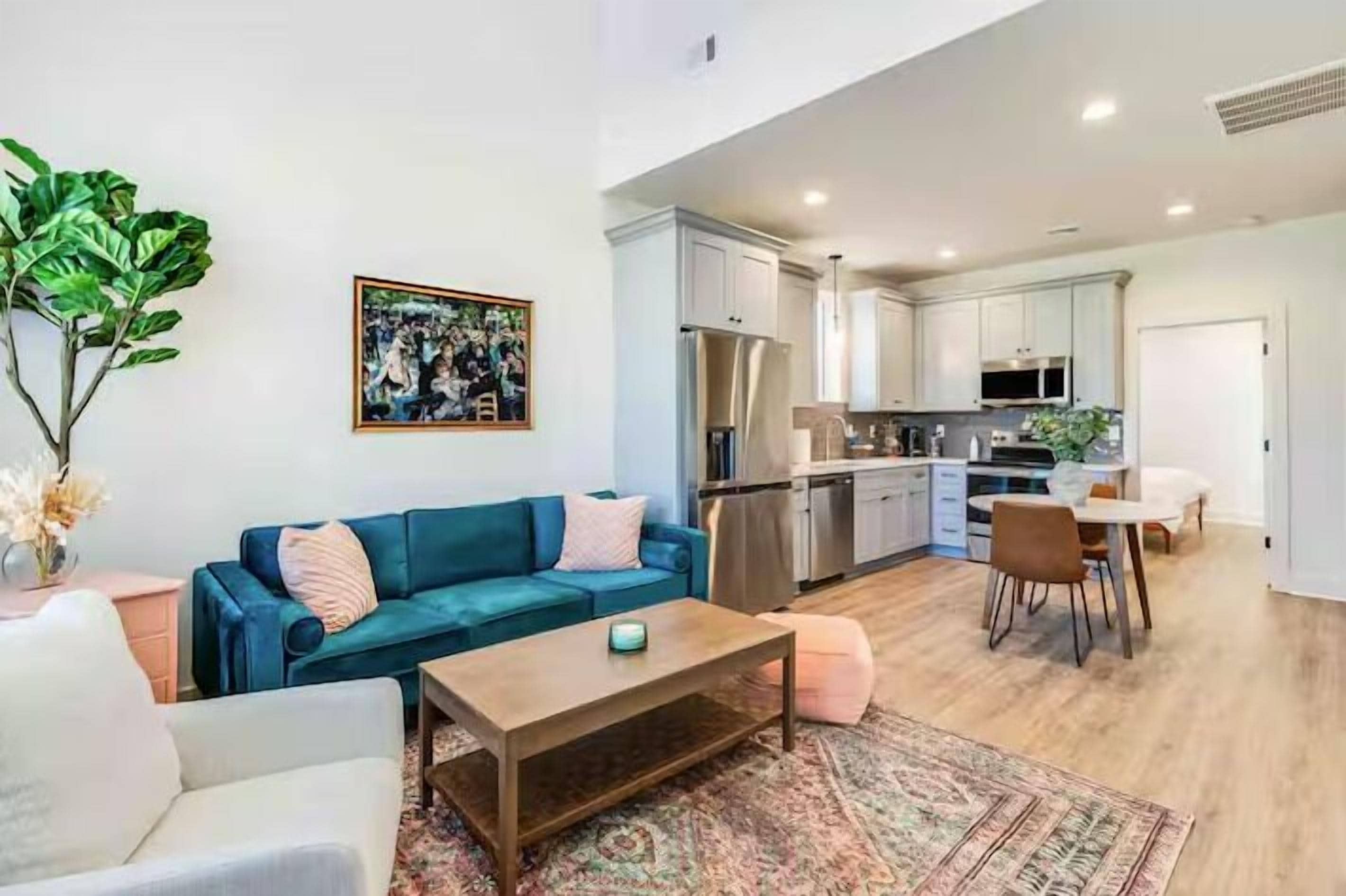 A modern living room with a sofa, coffee table, and a dining area with chairs and a table.
