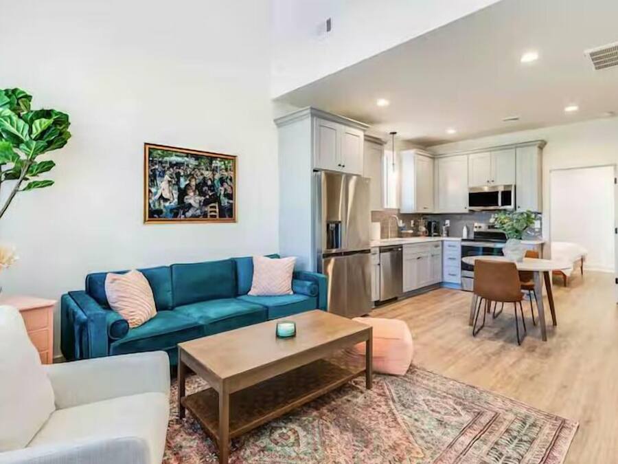 A modern living room with a sofa, coffee table, and a dining area with chairs and a table.