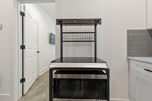 A compact kitchen with a built-in microwave, a small countertop, and a hanging rack.