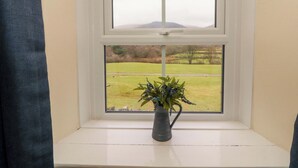 A window with a view of a grassy field and hills. - Easthwaite Cottage (Seascale)