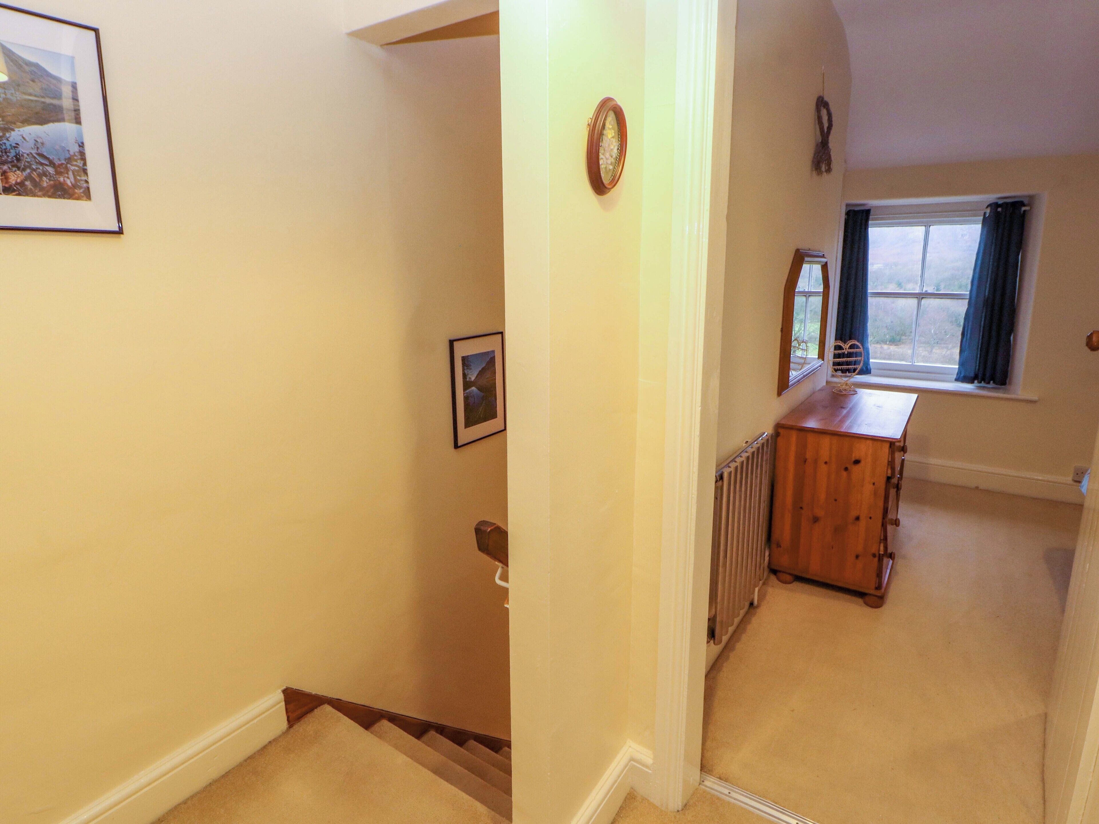 A hallway with a wooden dresser, a radiator, and a window with curtains.