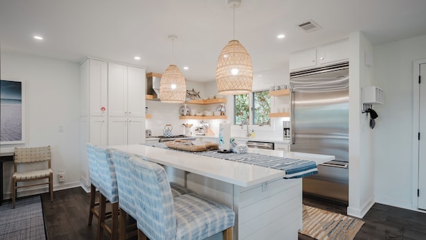 A modern kitchen with white cabinetry, a central island with bar stools, pendant lighting, and a stainless steel refrigerator. - 22 Sand Dollar - Koi Cottage: Island Serenity, 1st Row, Folly Field (Hilton Head Island)