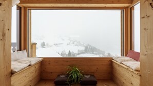 Quarto de cabana acolhedor com uma grande janela, paredes de madeira e um pequeno banco com uma planta.