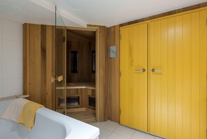A room with a wooden wardrobe, a white bathtub, and a wooden cabinet. - Les Gelinottes - Avec sauna privé (La Bresse)