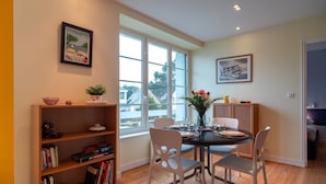 Un comedor con una mesa redonda, sillas blancas y una estantería con libros y objetos decorativos.