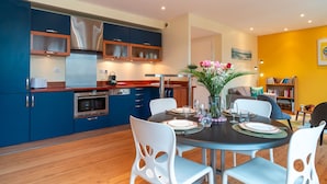 Una cocina moderna con gabinetes azules, una mesa de comedor para cuatro personas y un florero con flores.