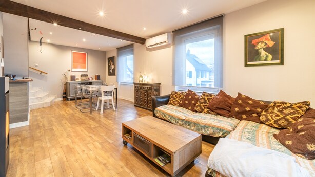 A modern living room with a sofa, coffee table, and dining area. - Le Repos du Rhin - 20min de Mulhouse (Niffer)