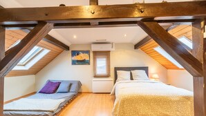 A bedroom with two beds, wooden beams, skylights, a painting, and a window with blinds. - Le Repos du Rhin - 20min de Mulhouse (Niffer)