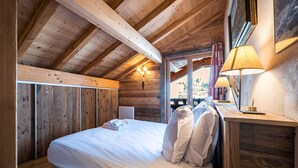 Ein Zimmer in einer Holzhütte mit einem Bett, zwei Wandlampen und einem Fenster mit Vorhängen.