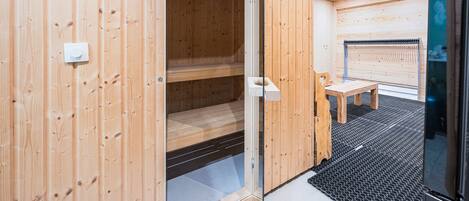 A sauna room with wooden walls and a bench.