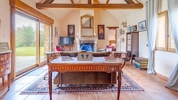 A spacious room with a large wooden table, a fireplace, and a view of the outdoors. - Coeur de Sologne - Proximité Châteaux de la Loire (Saint-Viâtre)