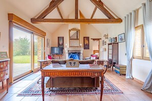 A spacious room with a large wooden table, a fireplace, and a view of the outdoors. - Coeur de Sologne - Proximité Châteaux de la Loire (Saint-Viâtre)