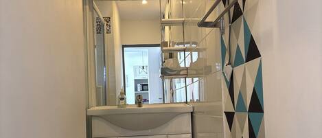 A modern bathroom with a white sink, mirror, and tiled walls.